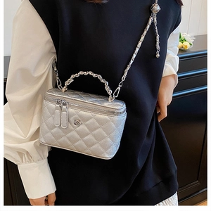 Détail du sac seau matelassé argenté avec logo floral et bandoulière chaîne