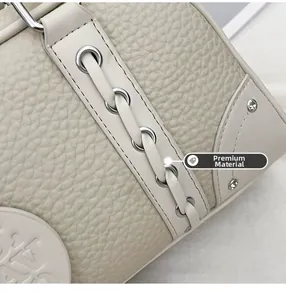 Detail of premium off-white lychee pattern leather with embossed logo and fine stitching