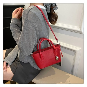 Détail d'un sac seau en cuir rouge avec pendentif coeur doré et cordon de serrage