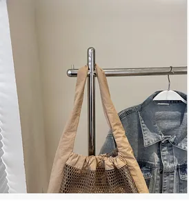 Detail of reinforced wide handles and hollow mesh design on a beige tote bag
