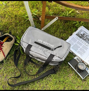 Close-up of a nylon sports crossbody bag with a wide strap on grass during camping