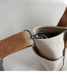 Détail du sac en toile avec bandoulière tissée marron et mousqueton en métal foncé