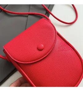 Gros plan d'un sac besace rouge en cuir grainé montrant les coutures et la texture