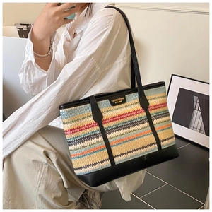 Detail of colorful striped straw tote with black leather trim and gold brand logo