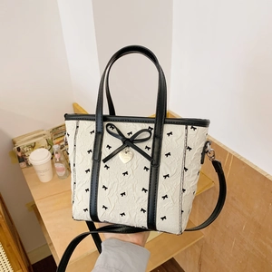 Détail du sac plissé blanc avec garniture en cuir noir, nœud et breloque en cœur