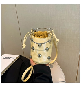 Detail der gelben Beuteltasche mit silbernen Metallnieten und Doppelgriffdesign
