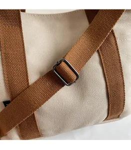 Détail de la bandoulière marron réglable avec boucle en métal gris foncé sur sac en toile