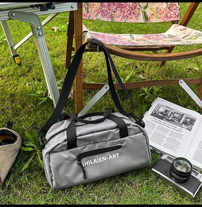 Outdoor close-up of a grey grid nylon crossbody sports bag with black handles and strap