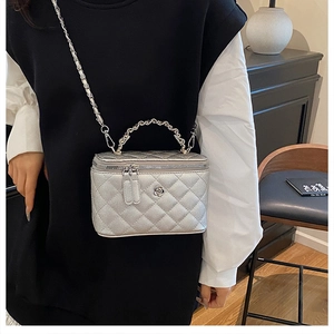 Détail du vanity bag argenté avec poignée en chaîne métallique et breloque fleurie