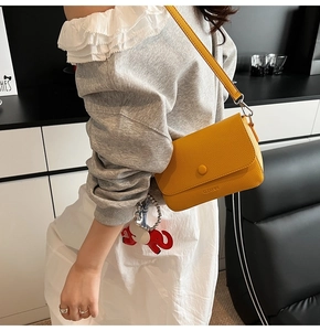 Detail of yellow lychee pattern leather shoulder bag with a cute red elephant charm