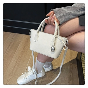 Détail du sac seau blanc en cuir grainé avec breloque cœur argentée et bandoulière