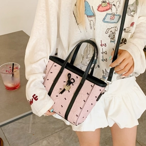 Détail du sac seau rose avec nœuds noirs et pendentif cœur sur similicuir texturé