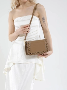 Brown faux leather crossbody bag featuring woven trim and adjustable shoulder strap