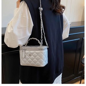 Gros plan du sac argenté matelassé avec bandoulière chaîne et détail floral