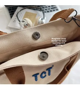 Détail du sac en toile avec fermoir magnétique et logo TCT brodé sur le devant