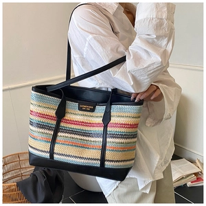 Detail of colorful striped woven tote bag with premium black leather straps and gold logo