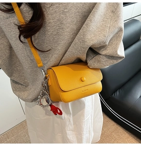 Detail of yellow lychee texture leather mini crossbody bag with metal chain charm