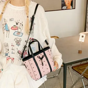 Détail du sac cabas en nylon rose avec motifs de nœuds noirs et bandoulière réglable