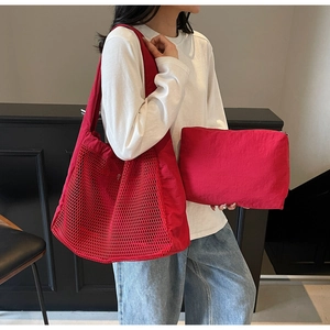Detail view of red hollow mesh tote bag with matching inner pouch on a model arm