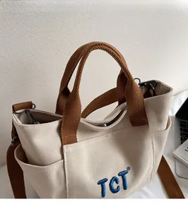 Détail du sac à main en toile avec broderie TCT et poignées en sangle marron