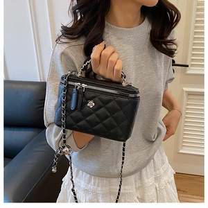 Détail du sac vanité noir matelassé avec fleur argentée et bandoulière chaîne