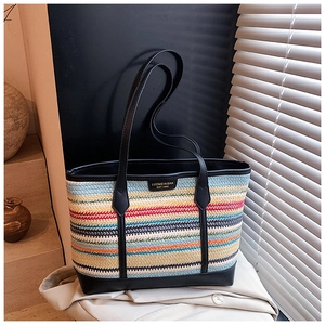 Detail of the colorful woven straw tote bag with black leather trim and metal brand plaque