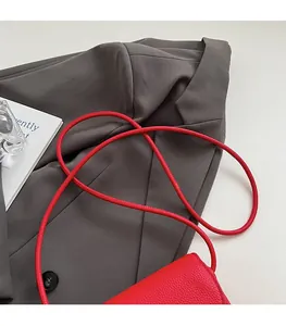 Vue détaillée du cuir rouge à grain litchi et de la fine bandoulière ronde du sac
