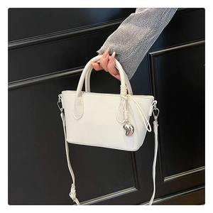 Détail du sac seau en cuir grainé crème avec breloque cœur et bandoulière amovible