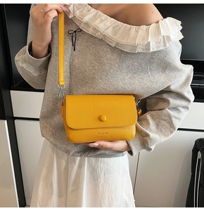 Detail of yellow lychee texture crossbody bag featuring engraved CLEAR OK text