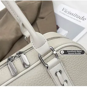 Detail of square silver metal buckle and lychee textured leather on white shoulder bag