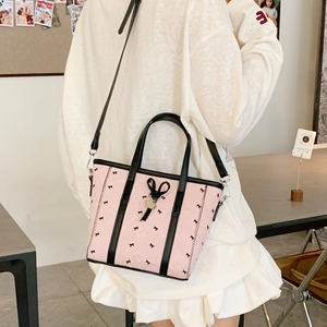 Vue latérale du sac fourre-tout rose en nylon avec nœuds noirs portés par le mannequin