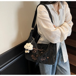 Close-up of black tote bag with cute pink cat embroidery and a white cloud plush charm