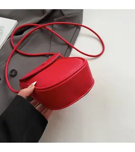 Détail d'un petit sac besace rouge en cuir grainé avec base plate et fine bandoulière