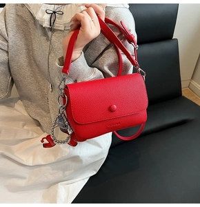 Close-up of red lychee textured leather crossbody bag with silver ball charm