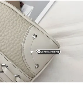 Detail of fine stitching and silver studs on beige leather shoulder bag corner