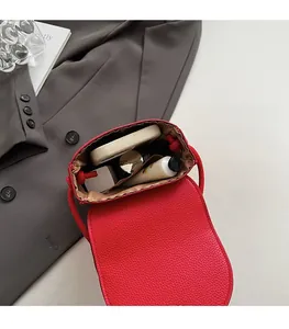Vue intérieure du sac bandoulière rouge avec texture litchi contenant du maquillage