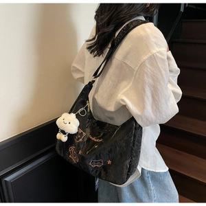 Close-up of black pleated crossbody bag with pink cat embroidery and fluffy cloud charm