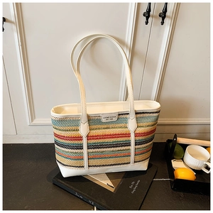 Detail of multi-color rainbow straw woven tote bag with white leather handles and logo