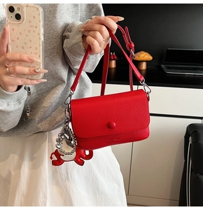 Detail showing the red pebble leather texture and a cute white elephant charm on the bag