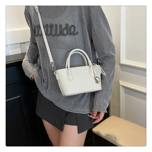 Détail d'un mini sac seau en cuir grainé blanc avec breloque cœur sur un mannequin
