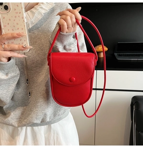 Détail du sac bandoulière en cuir grainé rouge avec rabat et fermeture à bouton