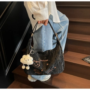Detail of black pleated tote bag featuring pink MashaKeke cat embroidery and cloud charm