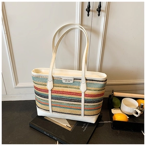 Detail of colorful rainbow straw tote bag with white leather handle on a stylish background