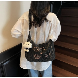 Detail of black pleated crossbody bag with pink cat embroidery and plush cloud charm