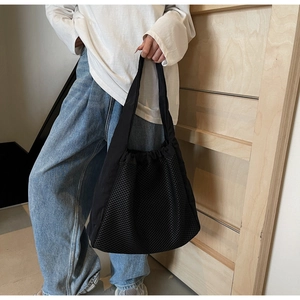 Detail of black mesh tote bag with drawstring closure and breathable hollowed-out texture