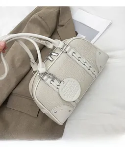 Close-up of cream lychee leather handbag with silver dual zippers and logo pendant charm