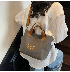 Détail du sac cabas en toile grise avec broderie TCT jaune et bandoulière marron