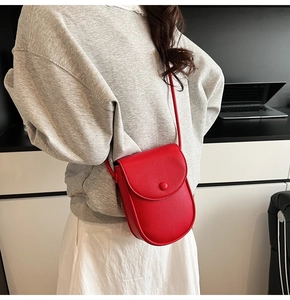 Détail du petit sac bandoulière rouge avec texture cuir grainé et rabat boutonné élégant