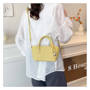 Détail du sac seau en cuir jaune à motif litchi avec breloque croissant argentée