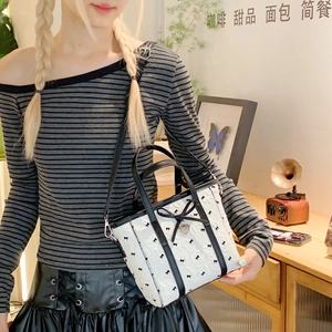 Gros plan du sac seau en nylon blanc avec nœuds noirs et pendentif cœur dans un café